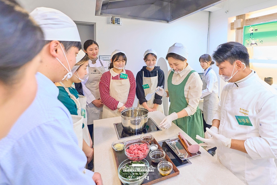 김혜경 여사가 1월 15일 서울 종로구 한식문화공간 이음에서 열린 자립준비청년들을 위한 생일상 차리기 행사에서 참석자들과 음식을 만들고 있다.