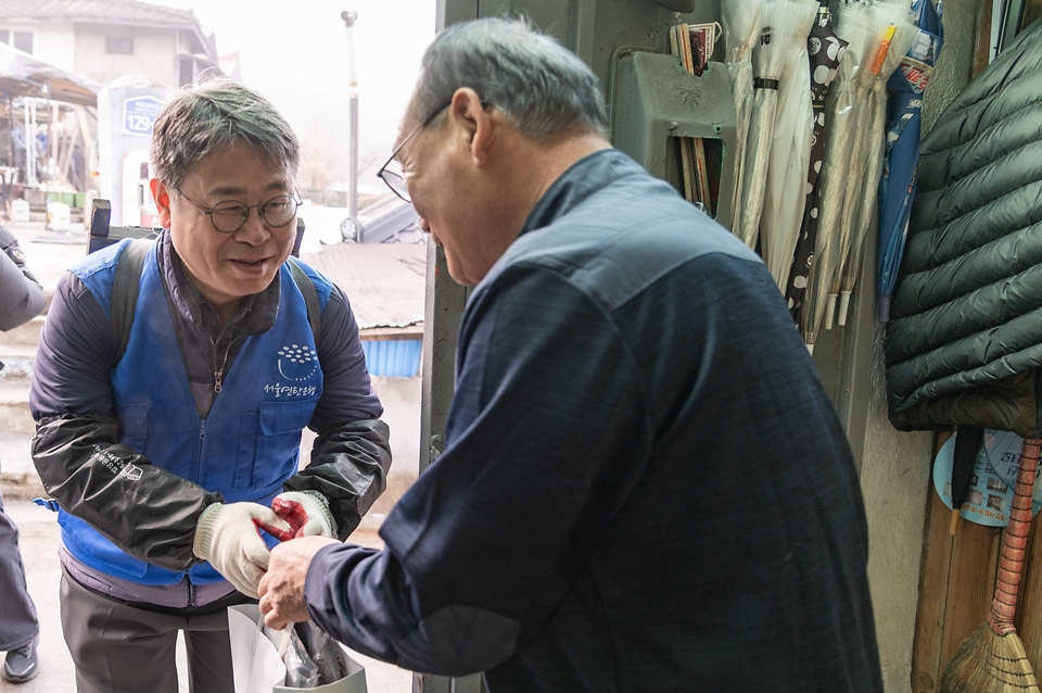 이정환 기상청 차장이 1월 16일 서울 서대문구 홍제동 개미마을을 찾아 한파 취약 가구를 찾아 방한용품을 전달하고 있다.