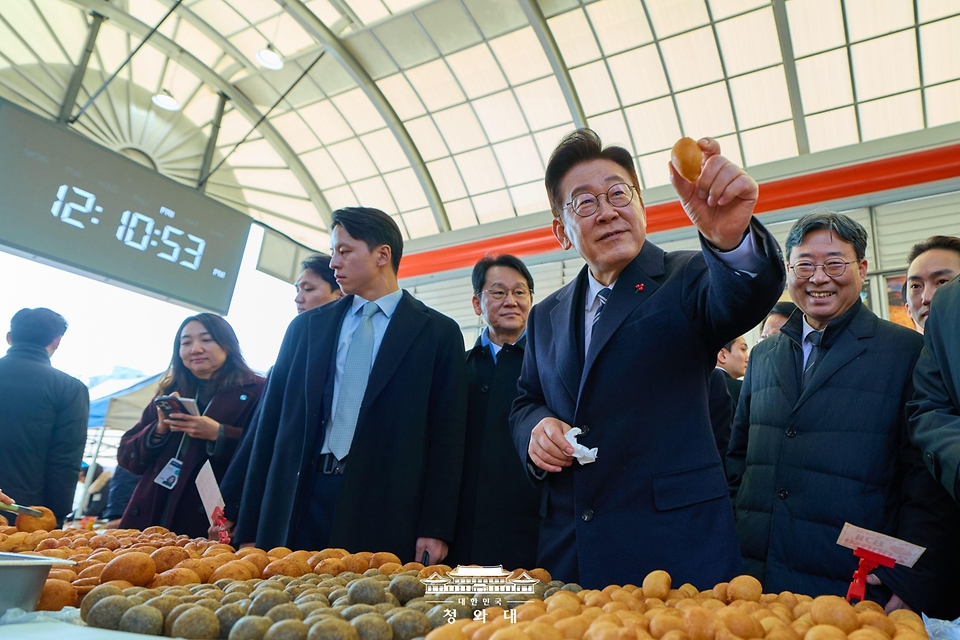 이재명 대통령이 1월 23일 울산 울주군 온양읍 남창옹기종기시장을 방문해 음식을 구매하고 있다.