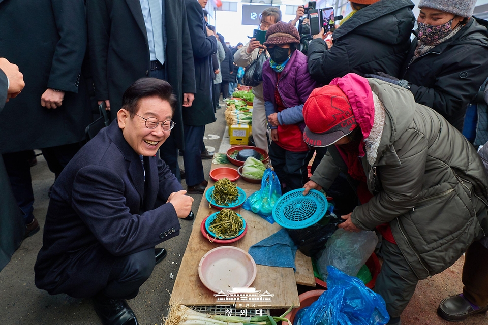 이재명 대통령이 1월 23일 울산 울주군 온양읍 남창옹기종기시장을 방문해 나물을 구매하고 있다.