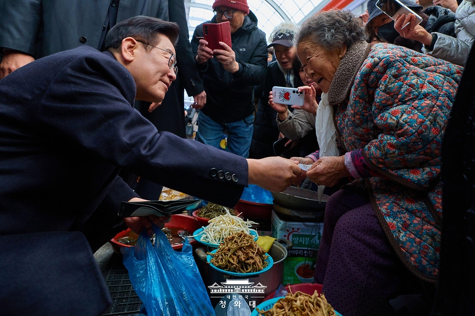 이재명 대통령이 1월 23일 울산 울주군 온양읍 남창옹기종기시장을 방문해 나물을 구매하고 있다.