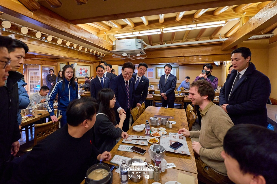 이재명 대통령이 2월 12일 홍익표 정무수석 등 참모진과 오찬을 위해 방문한 청와대 인근 삼계탕 집에서 식당 손님과 인사를 나누고 있다. 
