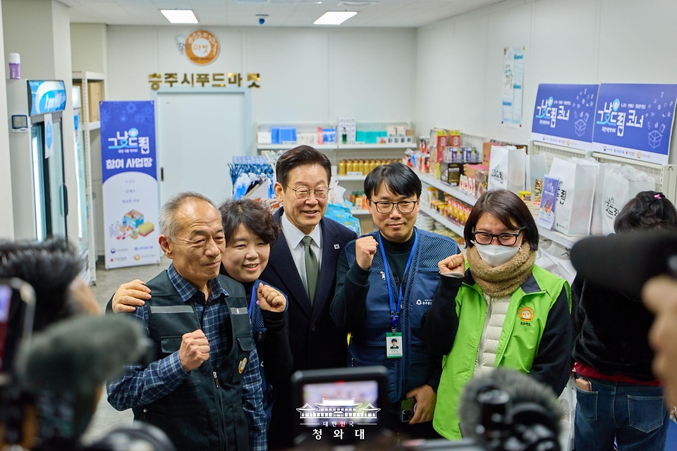 이재명 대통령과 2월 11일 충북 충주시건강복지타운 그냥드림 사업장을 방문해 관계자들과 기념 사진을 찍고 있다.