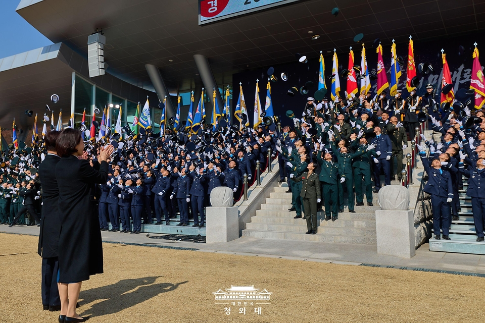 이재명 대통령과 김혜경 여사가 2월 20일 충남 계룡대 대연병장에서 열린 육·해·공군 사관학교 통합임관식에서 모자를 던지며 자축하는 신임 장교들을 격려하고 있다.