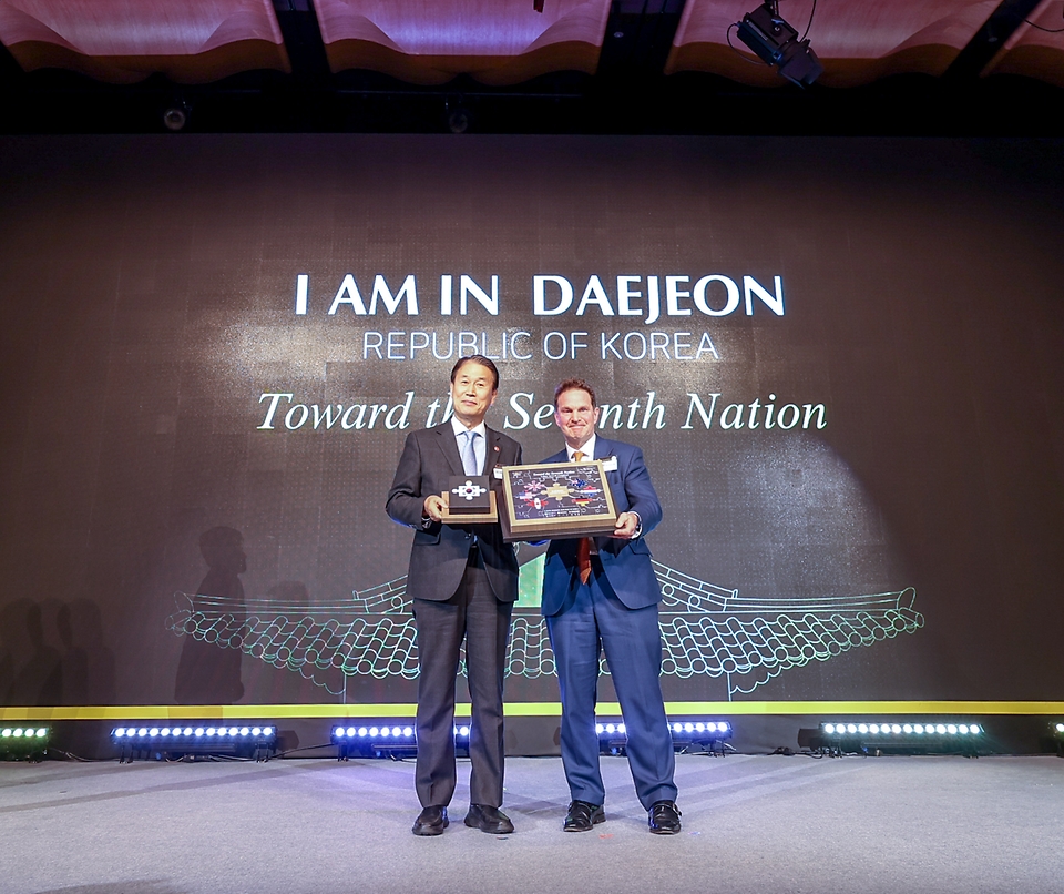 권오을 국가보훈부 장관이 2월 26일 오후 서울시 중구 더플라자호텔에서 열린 인빅터스재단 실사단 방한 만찬에 참석해 롭 오웬 재단 대표와 함께 유치 의지 전달 퍼포먼스를 하고 있다.