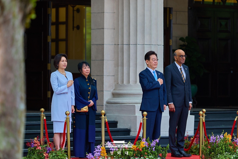 이재명 대통령과 김혜경 여사가 3월 2일(현지 시간) 싱가포르 외교부 청사에서 열린 국빈방문 공식환영식에서 국기에 경례하고 있다.
