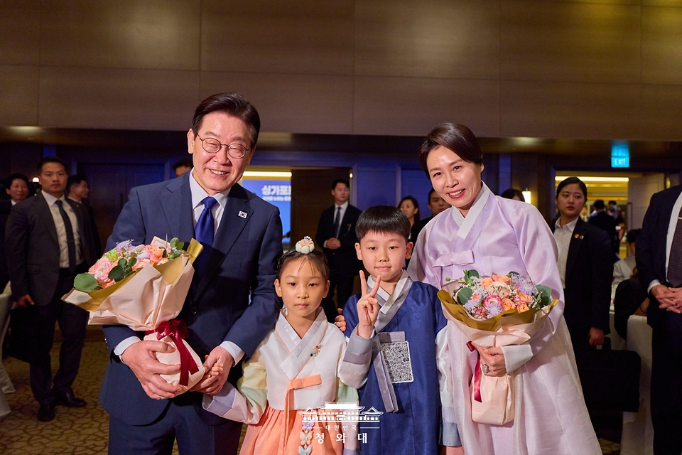 이재명 대통령과 김혜경 여사가 3월 1일 싱가포르 한 호텔에서 열린 동포 만찬간담회에서 화동과 기념촬영을 하고 있다.
