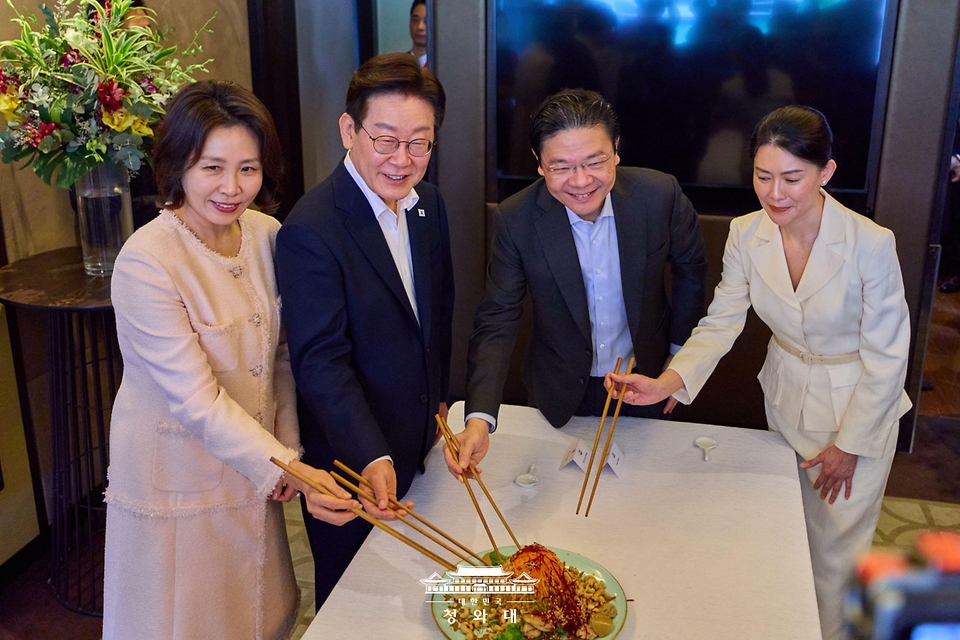 이재명 대통령과 김혜경 여사가 3월 2일(현지 시간) 싱가포르 한 호텔에서 로런스 웡 총리 부부와 친교 오찬에 앞서 싱가포르 새해 음식인 생선회 샐러드를 섞으며 덕담을 나누고 있다.