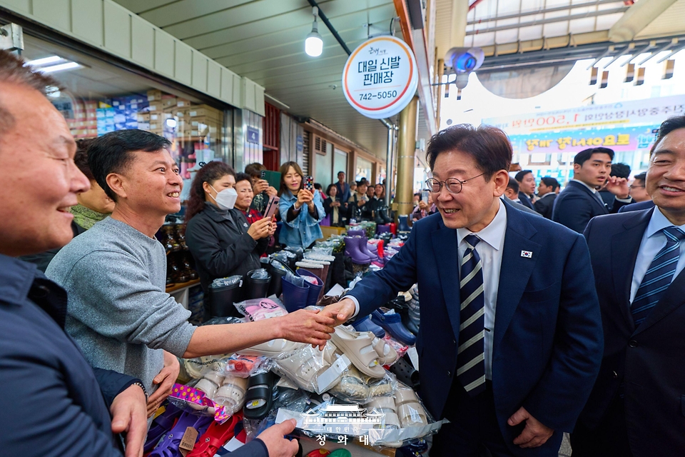 이재명 대통령이 3월 25일 한국항공우주산업(KAI)에서 열린 KF-21 양산 1호기 출고식에 참석한 뒤 경남 진주시 진주중앙시장을 방문해 상인과 악수하고 있다.