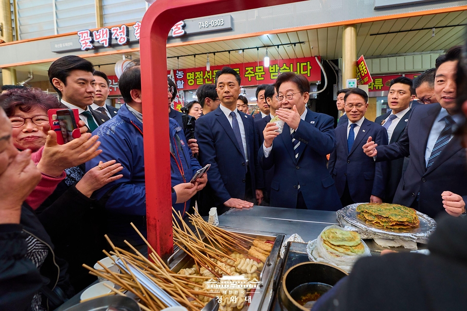 이재명 대통령이 3월 25일 한국항공우주산업(KAI)에서 열린 KF-21 양산 1호기 출고식에 참석한 뒤 경남 진주시 진주중앙시장을 방문해 음식을 맛보고 있다.