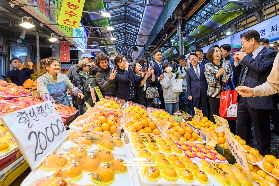 이재명 대통령이 3월 30일 제주 타운홀미팅을 마친 뒤 김혜경 여사와 함께 제주시 동문시장을 찾아 과일을 구매하고 있다.