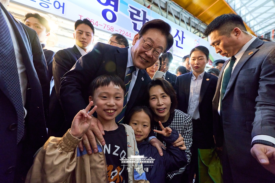 이재명 대통령이 3월 30일 제주 타운홀미팅을 마친 뒤 김혜경 여사와 함께 제주시 동문시장을 찾아 방문객들과 기념 촬영하고 있다.