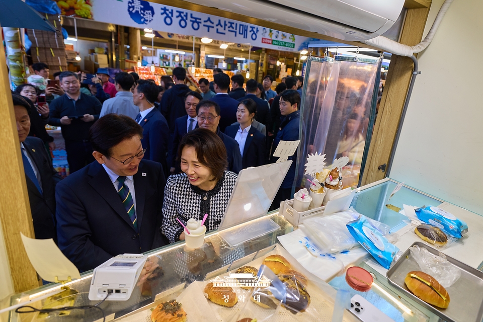 이재명 대통령이 3월 30일 제주 타운홀미팅을 마친 뒤 김혜경 여사와 함께 제주시 동문시장을 찾아 간식을 구매하고 있다.