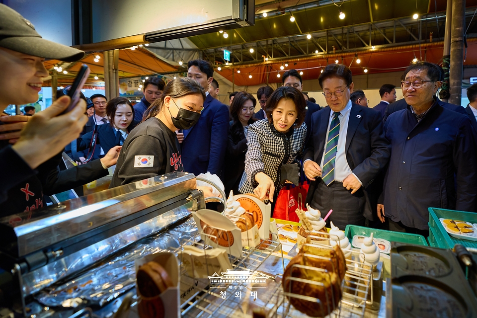 이재명 대통령이 3월 30일 제주 타운홀미팅을 마친 뒤 김혜경 여사와 함께 제주시 동문시장을 찾아 간식을 구매하고 있다.