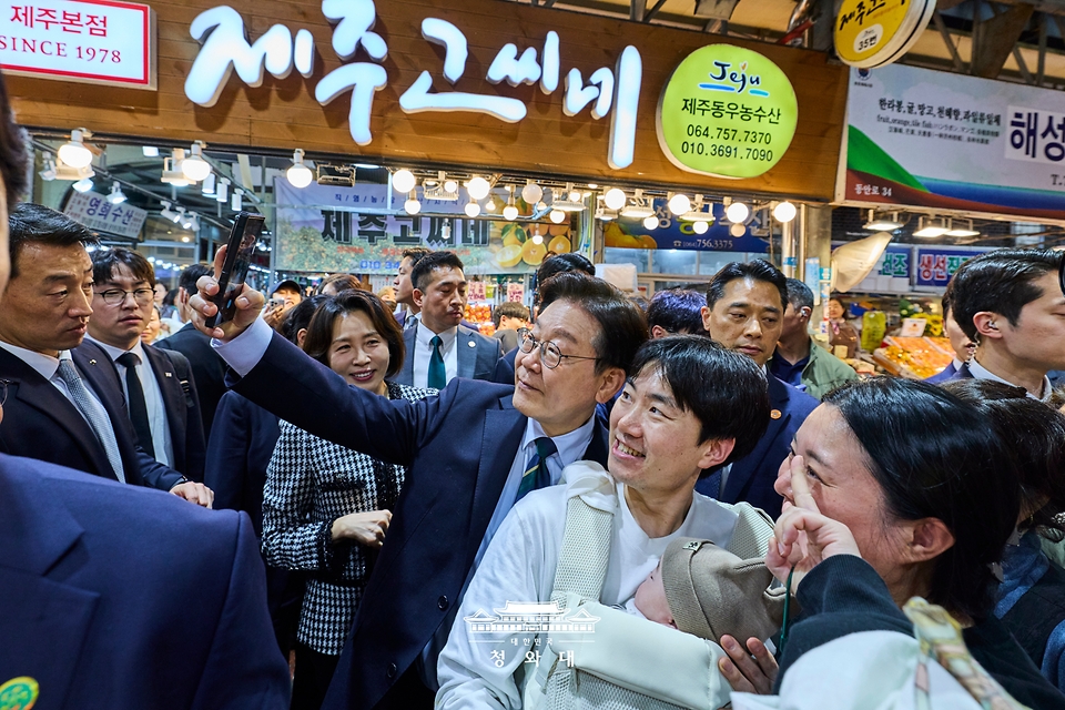 이재명 대통령이 3월 30일 제주 타운홀미팅을 마친 뒤 김혜경 여사와 함께 제주시 동문시장을 찾아 방문객들과 기념 촬영하고 있다.
