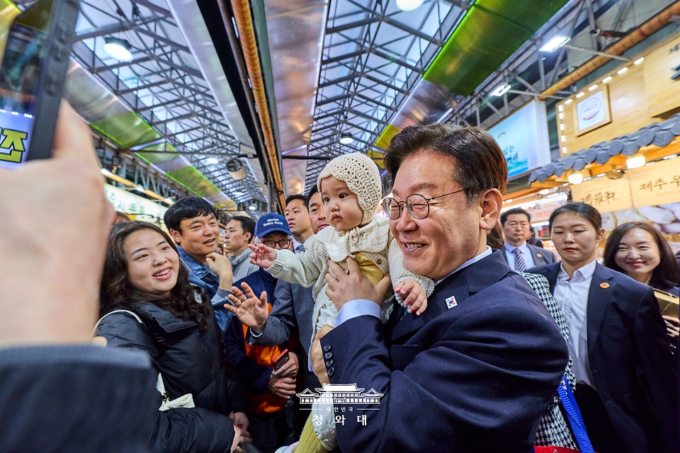 이재명 대통령이 3월 30일 제주 타운홀미팅을 마친 뒤 김혜경 여사와 함께 제주시 동문시장을 찾아 방문객들과 기념 촬영하고 있다.