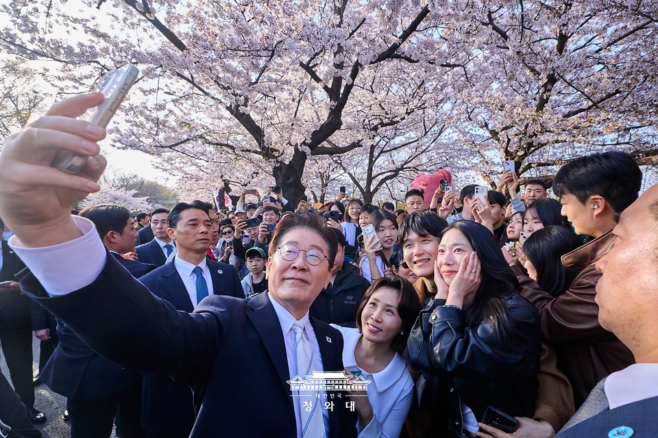 이재명 대통령과 김혜경 여사가 4월 5일 서울 여의도 윤중로에서 벚꽃을 배경으로 시민들과 기념촬영을 하고 있다.