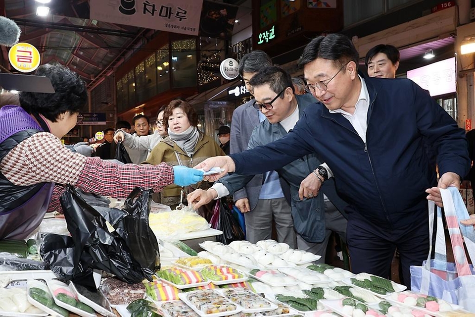 윤호중 행정안전부 장관이 4월 9일 서울 남구로시장을 방문해 비상경제대응 시장 물가 점검 등 물품 구매하며 상인들을 격려하고 있다.