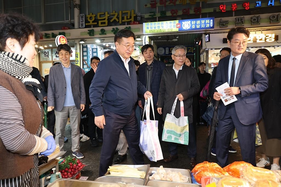 윤호중 행정안전부 장관이 4월 9일 서울 남구로시장을 방문해 비상경제대응 시장 물가 점검 등 물품 구매하며 상인들을 격려하고 있다.