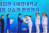 이재명 대통령이 5월 27일 부산 영도구에서 열린 제31회 바다의 날 기념식에서 귀항 보고를 한 해양대 실습생에게 꽃다발을 주고 있다.