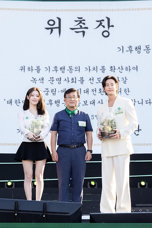 김성환 기후에너지환경부 장관이 6월 5일 서울 잠원한강공원에서 열린 2026 환경의 날 기념식에 참석해 아이들 미연과 영화배우 권율에게 기후행동 홍보대사 위촉장을 수여했다. 또한 주요 내빈들과 함께 대한민국 기후행동 출범식을 갖고, 기후행동 선언문을 낭독하고 기념촬영을 하고 있다.