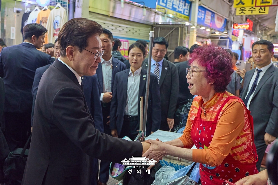 이재명 대통령이 6월 25일 수원 팔달문시장에서 상인들과 인사하고 있다.