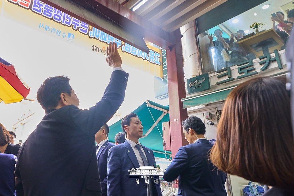 이재명 대통령과 김혜경 여사가 6월 25일 수원 팔달문시장에서 상인들과 인사하고 있다.