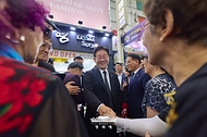이재명 대통령이 6월 25일 수원 팔달문시장에서 상인들과 인사하고 있다.