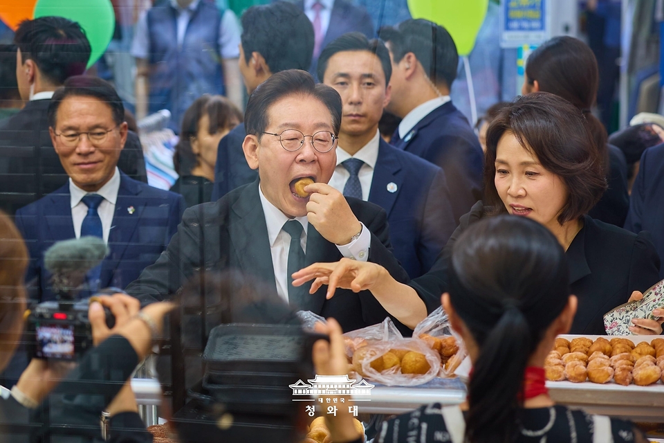 이재명 대통령과 김혜경 여사가 6월 25일 수원 팔달문시장에서 간식을 맛보고 있다.