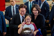 이재명 대통령과 김혜경 여사가 6월 25일 수원 팔달문시장에서 시민들과 기념 촬영하고 있다.