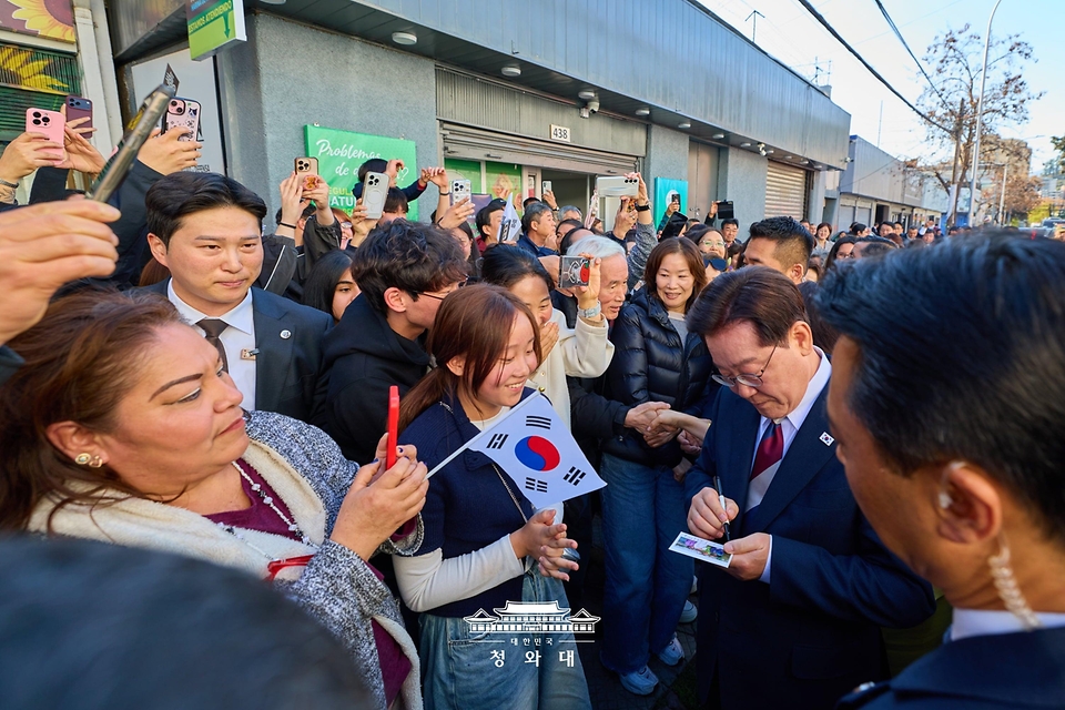 이재명 대통령이 7월 30일(현지 시간) 칠레 산티아고의 '한국의 거리'를 찾아 시민들에게 사인을 해주고 있다.