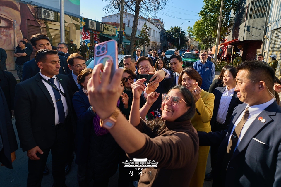 이재명 대통령과 김혜경 여사가 7월 30일(현지 시간) 칠레 산티아고의 '한국의 거리'를 찾아 시민들과 기념 촬영을 하고 있다.