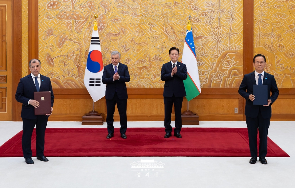 김종출 한국항공우주산업사장과 올림혼 루스타모프 우즈텍트레이드 대표가 9월 14일 청와대에서 이재명 대통령과 샤브카트 미르지요예프 우즈베키스탄 대통령이 임석한 가운데 방산 협력에 관한 계약 문건을 교환한 뒤 기념 촬영을 하고 있다.