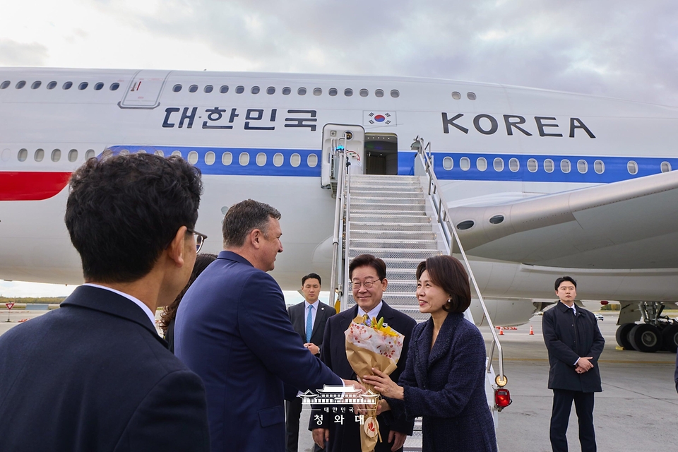 미국·멕시코 순방을 마친 이재명 대통령과 김혜경 여사가 9월 26일(현지 시간) 귀국길 경유지인 미국 알래스카주 앵커리지 테드 스티븐스 국제공항에서 영접 인사로부터 꽃다발을 받고 있다.