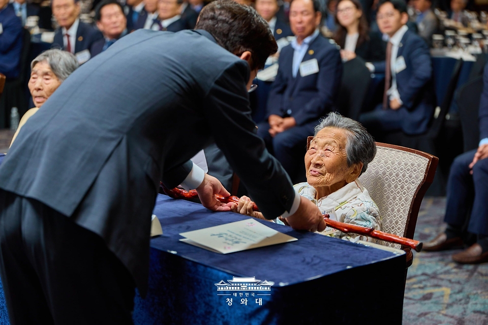 이재명 대통령이 10월 2일 서울 한 호텔에서 열린 제30회 노인의 날 기념식에서 100세 어르신들에게 명아주로 만든 지팡이인 청려장을 전달하고 있다.