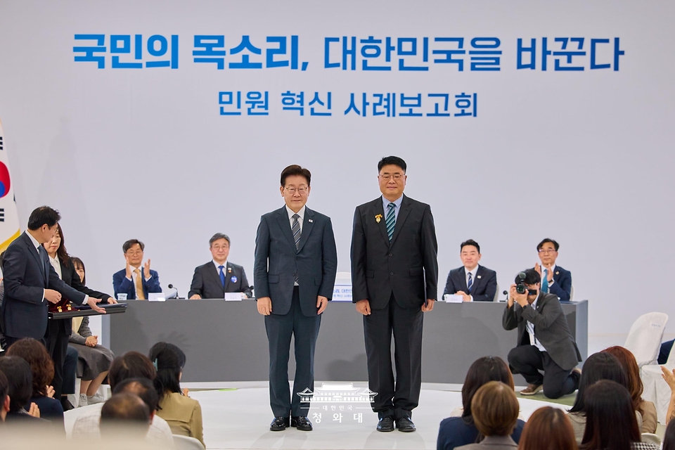 이재명 대통령이 10월 2일 세종특별자치시에서 열린 민원혁신 사례보고회에서 민원해결, 제도혁신 우수 공무원으로 선정된 김정환 경기도 화성시 주차시설팀장에게 대통령 표창을 수여한 뒤 기념촬영을 하고 있다.