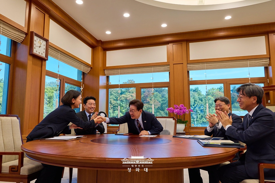 이재명 대통령이 10월 7일 청와대에서 한국형 발사체 누리호 5차 발사 성공 중계 화면을 보며 이해민 AI미래기획수석비서관과 악수하고 있다.