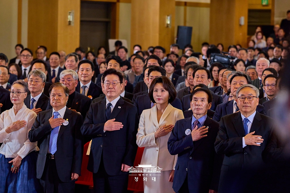 이재명 대통령과 김혜경 여사가 10월 16일 부산시청에서 열린 부마민주항쟁 47주년 기념식에서 국기에 경례하고 있다.