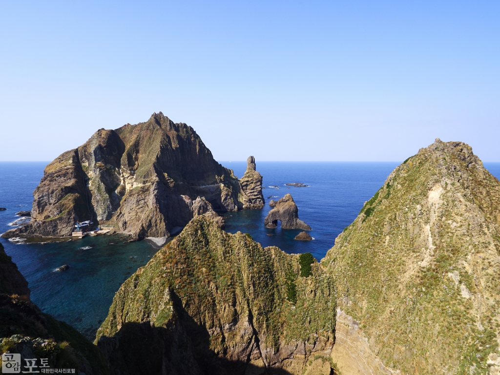 독도 동도(東島)의 천장굴 너머로 서도(西島)가 보인다. 천장굴은 바닷물이 오랫동안 드나들어 생긴 해식동굴이다. 
