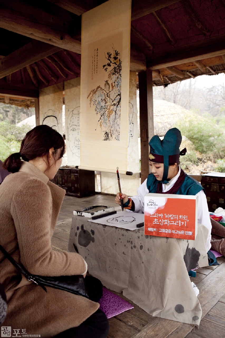 스크린과 브라운관을 종횡무진하고 있는 우리나라 사극을 체험해 볼 수 있는 '사극드라마축제'가 올해 3회를 맞이해 한국민속촌에서 개최되었다.</br>
행사는 영화와 드라마 속 명장면의 감동을 그대로 느낄 수 있도록 다양한 체험행사로 꾸며졌고, 영화 <관상>과 드라마 <바람의 화원>의 주인공인 관상쟁이와 화원이 등장해 관람객들에게 다양한 체험을 선사했다. 사진은 초상화체험을 하고있는 관람객의 모습.