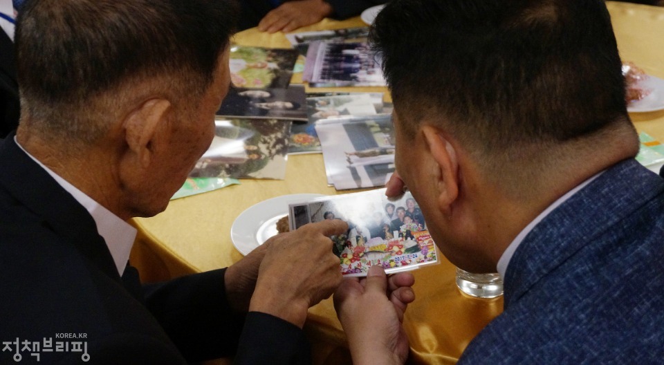 20일 금강산호텔에서 열린 제21차 남북 이산가족 단체상봉 행사에서 남측 김병선 할아버지가 두 조카를 만나 함께 사진을 보고 있다.
(사진=청와대) 