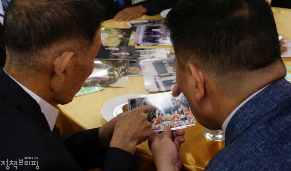 20일 금강산호텔에서 열린 제21차 남북 이산가족 단체상봉 행사에서 남측 김병선 할아버지가 두 조카를 만나 함께 사진을 보고 있다.
(사진=청와대) 