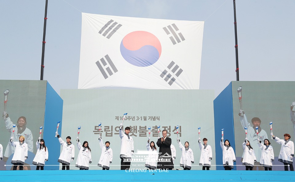 문재인 대통령이 3월 1일 오전 서울 광화문광장에서 열린 제100주년 3.1절 기념식을 마친 뒤 독립영웅 임우철 지사에게 받은 독립의 횃불을 청년 단장에게 전달하며 박수치고 있다.