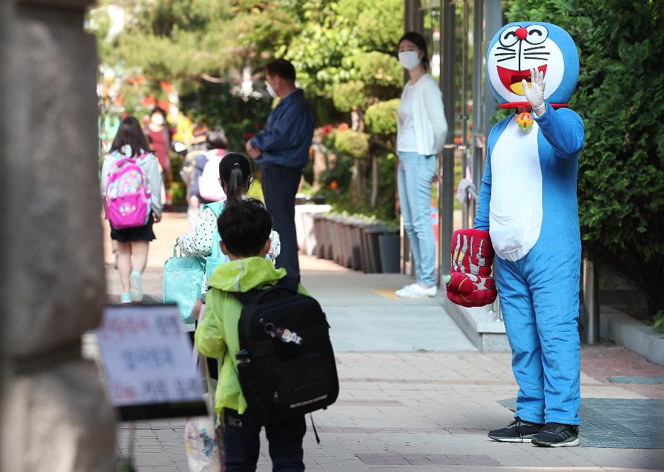 <p>27일 서울 동작구 보라매초등학교 1학년, 2학년 학생들이 코로나19 예방을 위해 선생님들의 안내로 후문과 정문을 통해 일정한 거리두기와 발열 체크를 하며 침착하게 등교해 수업에 참여하고 있다. 이날 교장선생님이 인기 있는 만화캐릭터 복장을 하고 학생들과 등교 인사를 하고 있다.</p>