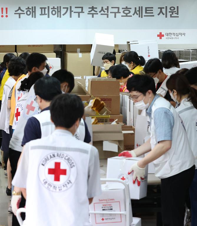 <p>17일 서울 성동구 대한적십자사 서울지사에서 적십자 직원 및 봉사원들이 전국 수해 가구에 전달할 추석구호세트 1,300여 개를 제작해 트럭에 싣고 있다. 구호세트는 마스크, 손소독제, 가공식품 등으로 구성되었다.</p>