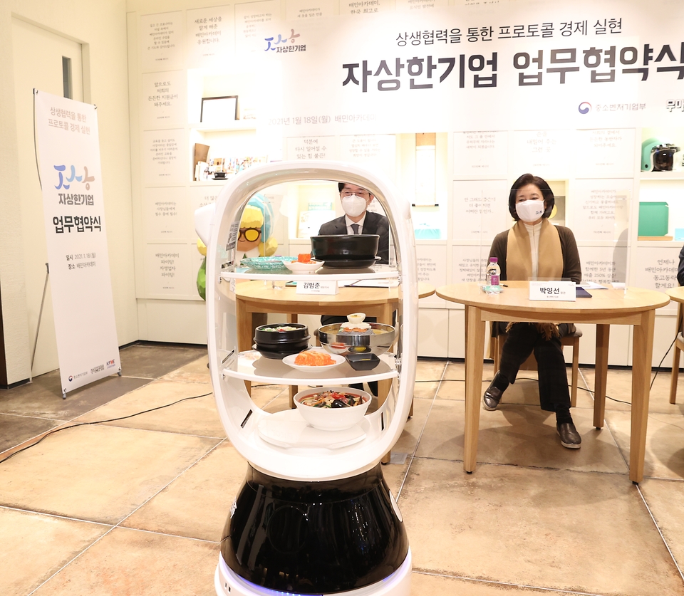 박영선 중소벤처기업부 장관(가운데)이 18일 서울시 송파구 배민아카데미에서 열린 ‘상생협력을 통한 프로토콜 경제 실현’을 위한 자상한 기업 업무협약식에서 협약서에 배달로봇이 배달한 서명펜을 받고 있다.