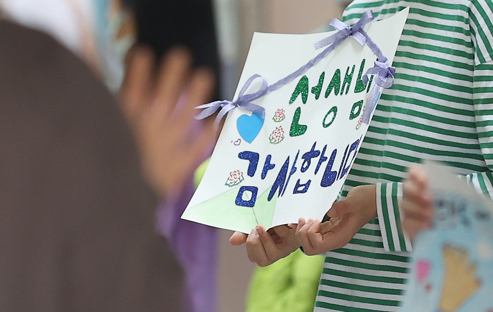 스승의 날을 하루 앞두고 서울 동작구 보라매초등학교 학생들이 교장 선생님과 함께 출근하는 선생님들에게 감사의 마음을 담은 팻말을 들어 보이며 인사하고 있다.