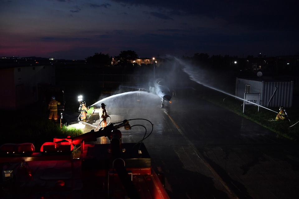 공군 38전투비행전대 소방구조반 요원들이 27일 야간 항공기 화재 상황을 가정한 훈련에서 F-5 전투기에 물을 뿌리고 있다.