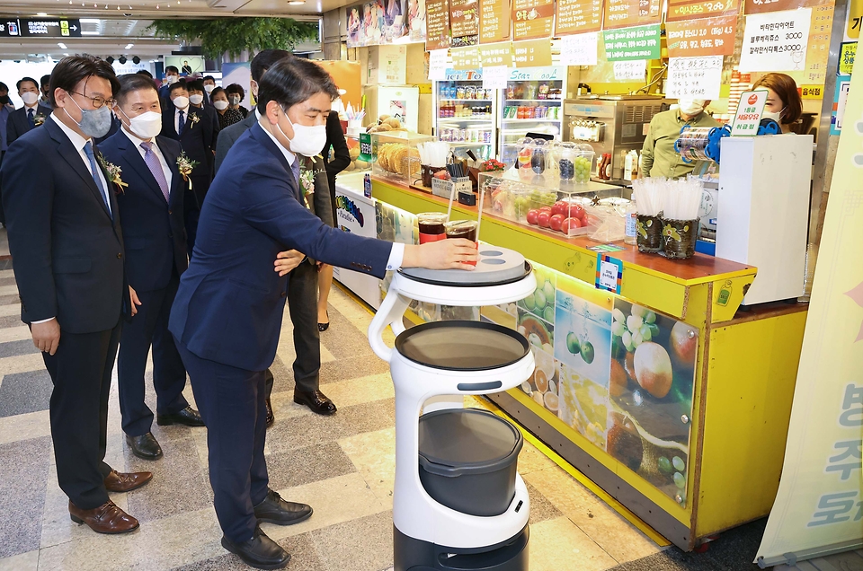 주영준 산업통상자원부 산업정책실장이 13일 대전광역시 중앙로 지하상가에서 열린 ‘AI·5G 기반 서비스로봇 융합모델 실증사업 출범식’에 참석하여, 로봇 시연을 참관하고 있다.