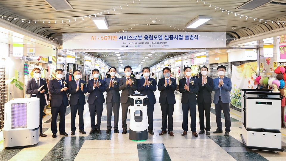주영준 산업통상자원부 산업정책실장이 13일 대전광역시 중앙로 지하상가에서 열린 ‘AI·5G 기반 서비스로봇 융합모델 실증사업 출범식’에 참석하여, 로봇 시연을 참관하고 관계자들과 기념 촬영을 하고 있다.